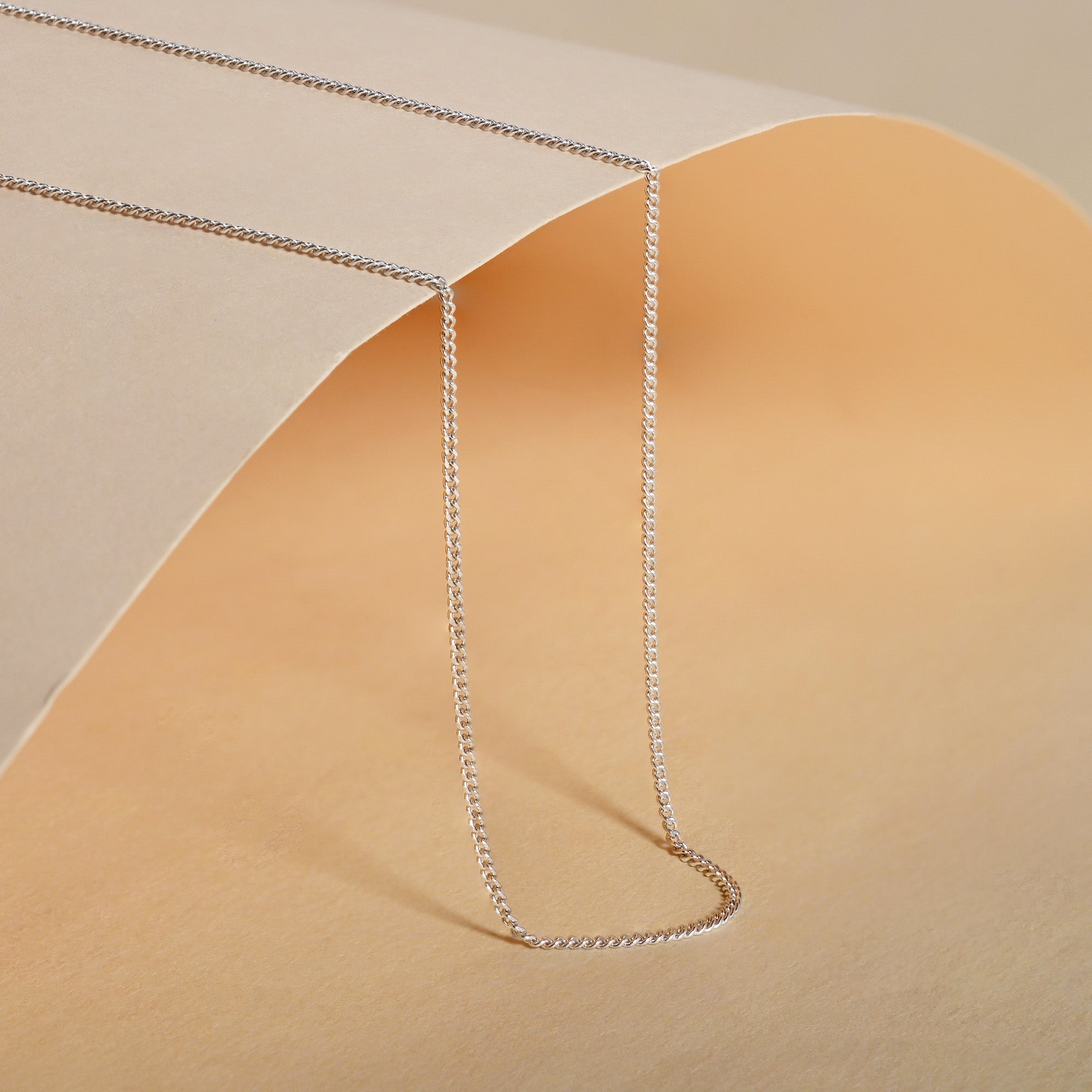 Silver chain necklace on a beige background