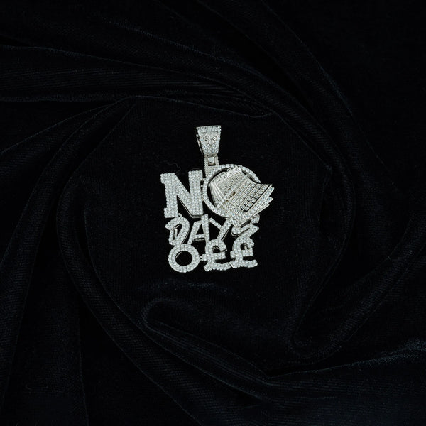 A No Days Off Zircon Studded Silver Locket by Touch 925 lies on black velvet fabric. The letters are in a bold font with intricate detailing, making it a prominent and luxurious jewelry piece. Crafted as a unique calendar design, it reminds you of your unwavering commitment every day.